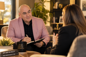Coach and professional in a supportive conversation, representing outside perspective that helps overcome self-doubt